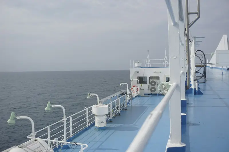 The outer deck of a ship sailing on a calm grey sea